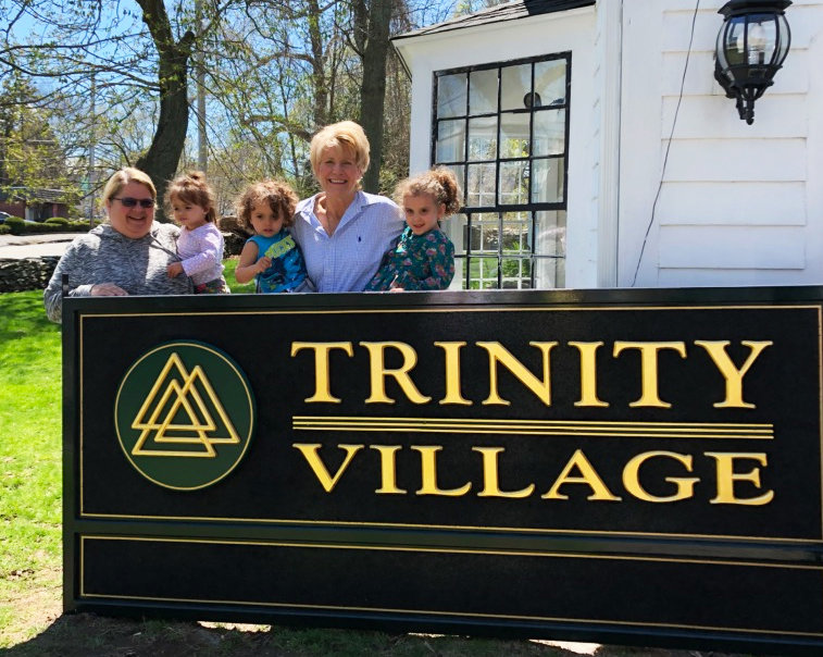 Holly Cekala, left, and Christine Nolan, fourth from left,  the CEO of Trinity Village, prepare to hang the sign for The Blessing Way.
